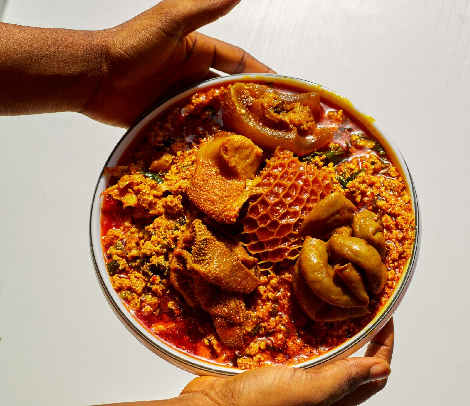 a bowl of egusi soup with cow skin, tripe and other assorted meat