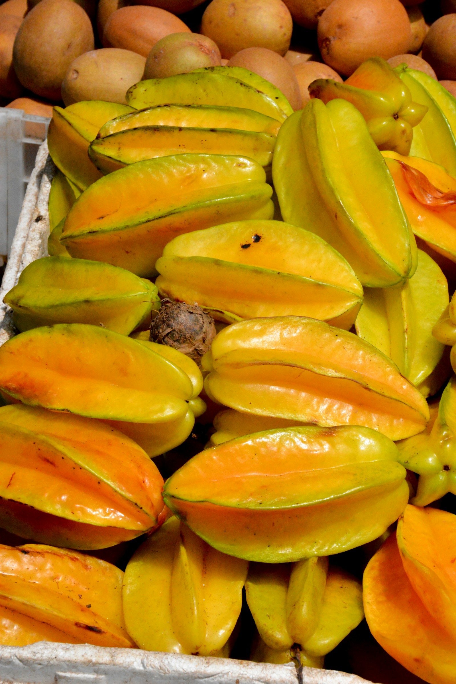 a pile of ripe yellow star fruit in a market crate